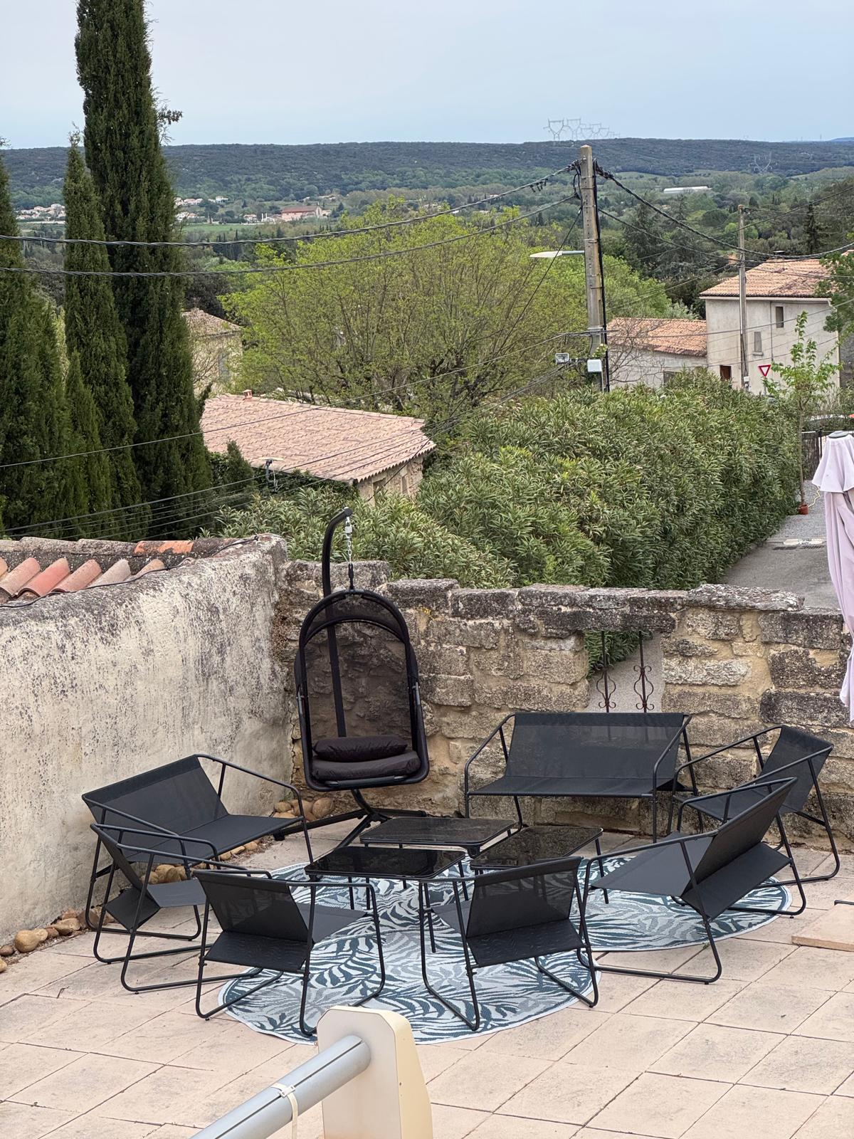 Salon d’extérieur en terrasse avec vue sur la garrigue et les toits du village
